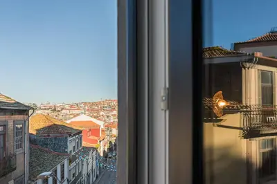 a bird on a window sill looking out at a city at Vila Rio Guest House in Vila Nova de Gaia
