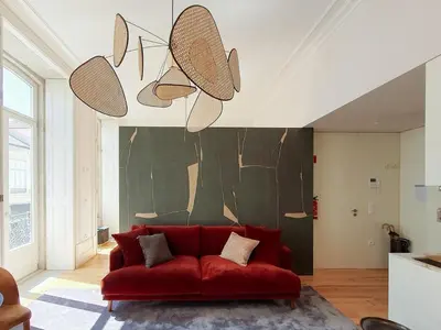 a living room with a red couch in front of a wall at Classic loft in fully renewed building at Batalha in Porto
