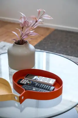 a remote control holder on a glass table with a vase at GuestReady - Marble Branch in Porto