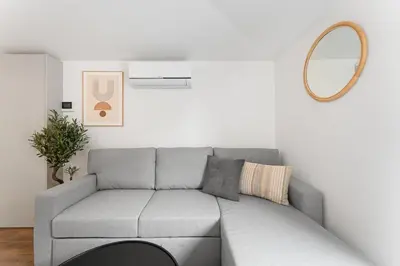 a living room with a gray couch and a mirror at Modern 1BR Apartment - Brand New Bonjardim I in Porto