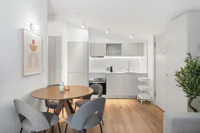 a living room with a table and chairs and a kitchen at Modern 1BR Apartment - Brand New Bonjardim I in Porto