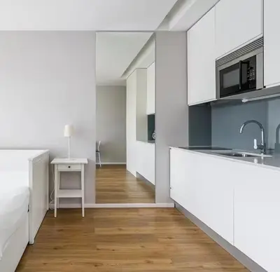 a kitchen with white cabinets and a wooden floor at Bolhão Luxe Retreat 2 in Porto