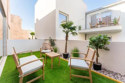 a patio with chairs and a table and palm trees at Stay Bonjardim - Modern Garden Duplex M in Porto