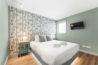 a bedroom with a large white bed with a wall at Stay Bonjardim - Modern Garden Duplex M in Porto