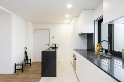 a kitchen with white walls and black countertops at GuestReady - comfort near Jardim do Morro in Vila Nova de Gaia