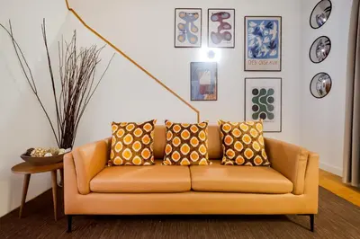 an orange couch in a living room with pictures on the wall at Duque 3 Luxury Apartment Downtown Porto near Metro in Porto