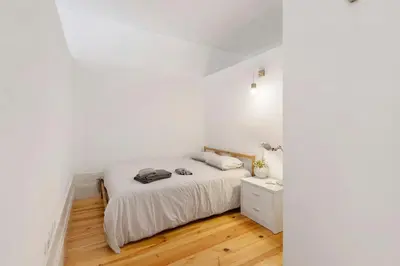 a bedroom with white walls and a bed and a wooden floor at Breiner House Porto in Porto