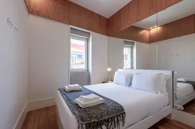 a bedroom with a large white bed with a mirror at Modern Flat with balcony on Rua das Flores - 5th in Porto