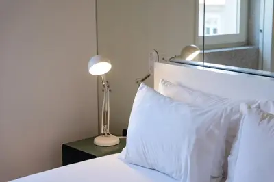 a bedroom with a bed with white pillows and a lamp at Modern Flat with balcony on Rua das Flores - 5th in Porto