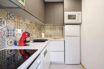 a small kitchen with white cabinets and a microwave at NEW! House with Hot Tub by Douro River & Iconic Bridge in Vila Nova de Gaia