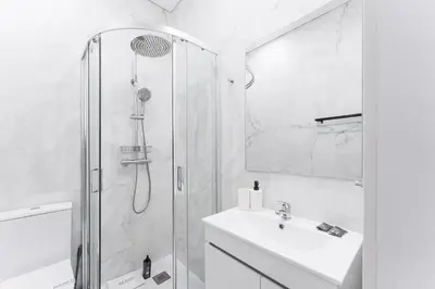 a white bathroom with a shower and a sink at GuestReady - Douro D'or Apartments in Vila Nova de Gaia
