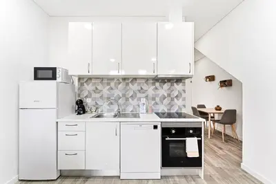 a white kitchen with a sink and a refrigerator at GuestReady - Douro D'or Apartments in Vila Nova de Gaia