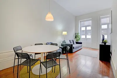 a living room with a table and chairs and a couch at Bright Cedofeita Flat with Balcony in Porto