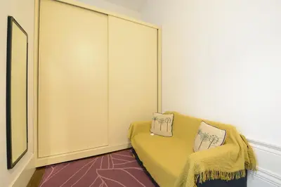 a room with a yellow couch with two pillows on it at Bright Cedofeita Flat with Balcony in Porto