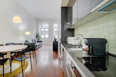 a kitchen with a table and a living room at Bright Cedofeita Flat with Balcony in Porto