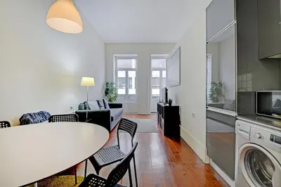 a kitchen and living room with a table and chairs at Bright Cedofeita Flat with Balcony in Porto