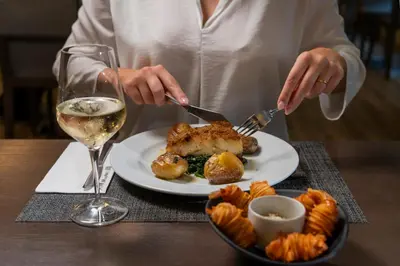 a person eating a plate of food with a glass of wine at HF Ala Sul in Porto
