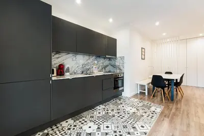 a kitchen with black cabinets and a table and a kitchen rug at GuestReady - Cosy family home in the Bonfim area in Porto