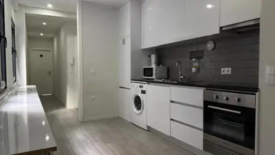 a kitchen with white cabinets and a washer and dryer at Classic Freitas in Porto
