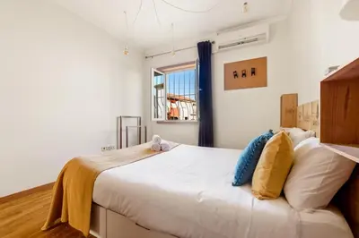 a bedroom with a large white bed and a window at 2 Bdr Guadiana House Garden Metro Station 2min in Porto