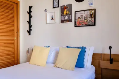 a white bed with pillows and pictures on the wall at 2 Bdr Guadiana House Garden Metro Station 2min in Porto