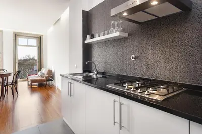 a kitchen with white cabinets and a black counter top at Belly Angel - Porto Historic Center in Porto