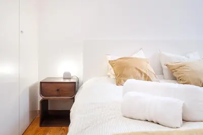 a bed with white sheets and pillows and a side table at The Cozy Loft in Porto
