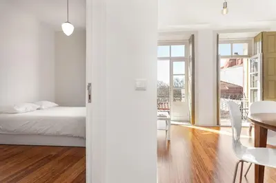 a white bedroom with a bed and a dining room at Egg Nuts Apartment in Porto
