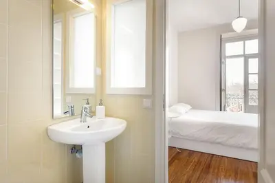 a bathroom with a sink and a bed in a room at Egg Nuts Apartment in Porto