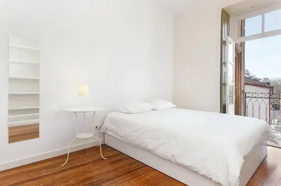 a white bedroom with a white bed and a window at Egg Nuts Apartment in Porto