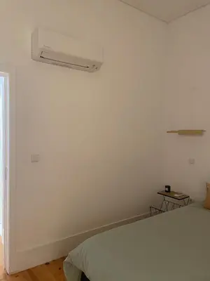 a bedroom with a white wall and a bed at Quiet, bright apt near Bolhão in Porto
