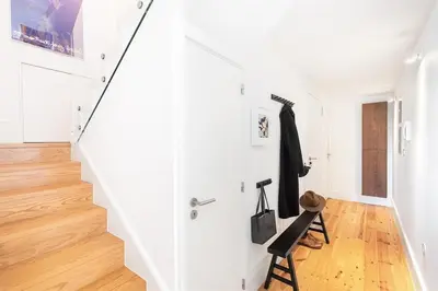 a white staircase in a white room with a chair at Sol Do Porto - 2 bed Penthouse Luis Bridge view in Porto