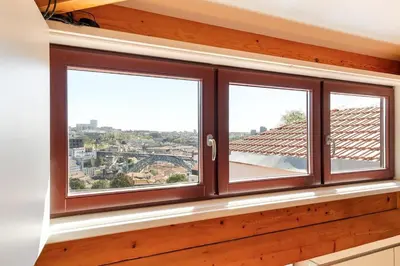 two windows in a room with a view of a city at Sol Do Porto - 2 bed Penthouse Luis Bridge view in Porto