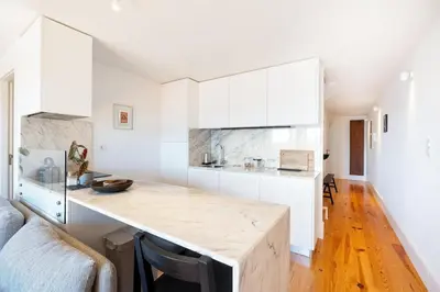 a kitchen with white cabinets and a wooden counter top at Sol Do Porto - 2 bed Penthouse Luis Bridge view in Porto