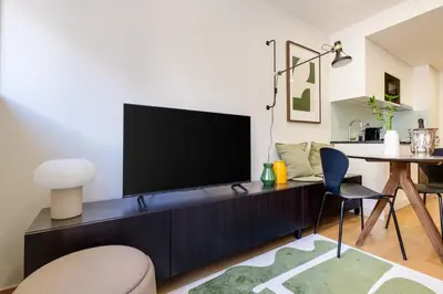 a living room with a flat screen tv on a cabinet at Camoes Apartment with AC near Metro in Porto