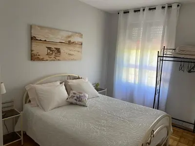 a bedroom with a bed with white sheets and a window at House T3 in Vila Nova de Gaia