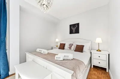 a white bedroom with a large white bed and a chandelier at GuestReady - Cosy Porto retreat in Porto