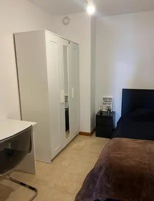 a bedroom with a bed and a desk and a cabinet at Quarto no centro do Porto in Porto