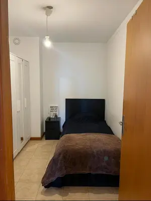 a bedroom with a bed in a white room at Quarto no centro do Porto in Porto