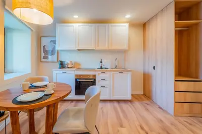 a kitchen with white cabinets and a wooden table at Douro Prestige Studio in Vila Nova de Gaia