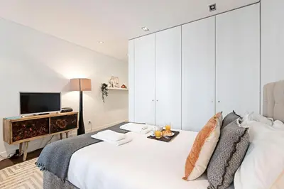 a white bedroom with a large bed and a television at Carlos Alberto Apartment in Porto