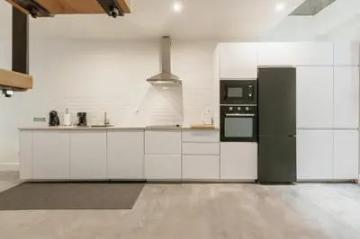 a kitchen with white cabinets and a black refrigerator at Urban Refuge 4BD by Vacationy in Porto