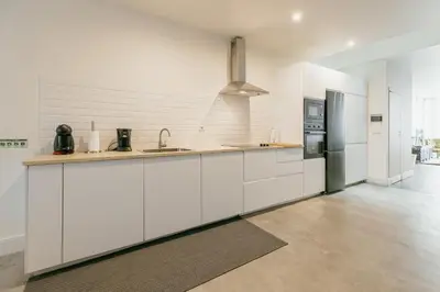 a white kitchen with a sink and a refrigerator at Urban Refuge 4BD by Vacationy in Porto