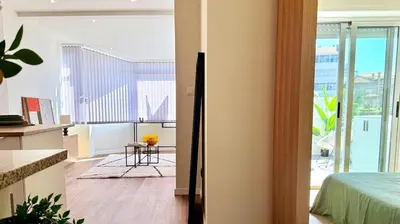 a room with a bed and a kitchen with a balcony at Essence Santa Catarina Flat in Porto