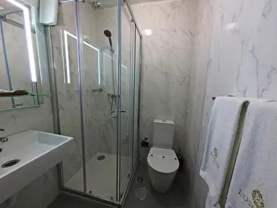 a bathroom with a shower and a toilet and a sink at Lusitana Hotel in Porto