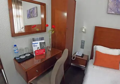 a hotel room with a bed and a desk with a mirror at Lusitana Hotel in Porto