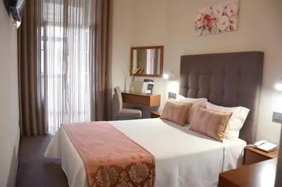 a hotel room with a large bed and a desk at Lusitana Hotel in Porto