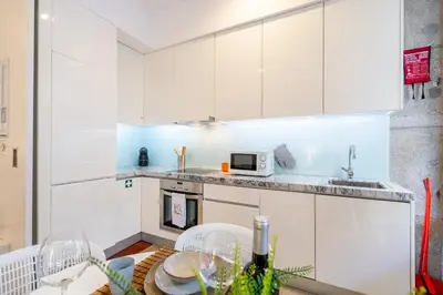 a kitchen with white cabinets and a table with chairs at Merc Porto Clérigo's Place in Porto