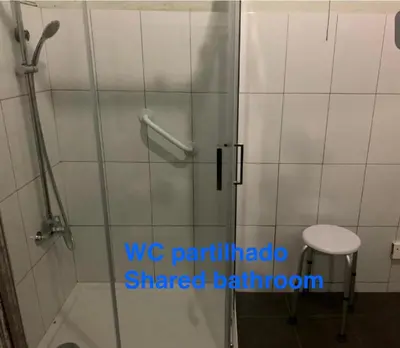 a shower with a glass door and a stool in a bathroom at Residência Céu Azul in Porto