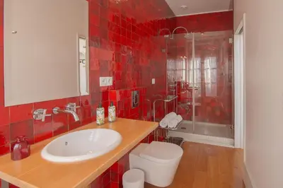 a red tiled bathroom with a sink and a toilet at Fil's Place in Porto
